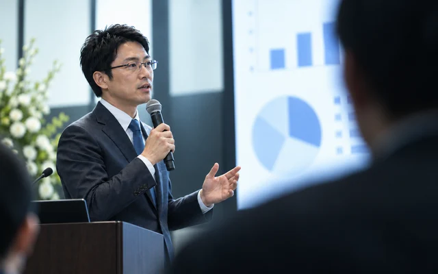 登壇者がスクリーンの図表を使って導入事例を紹介するイメージ